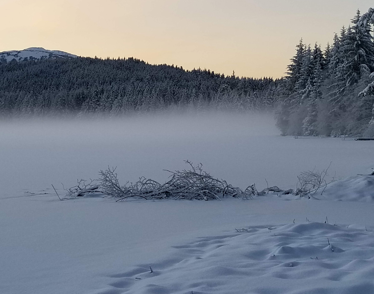 Scenic landscape shot of Auke Lake in Juneau Alaska after it snowed and the lake is steaming above the fresh snow